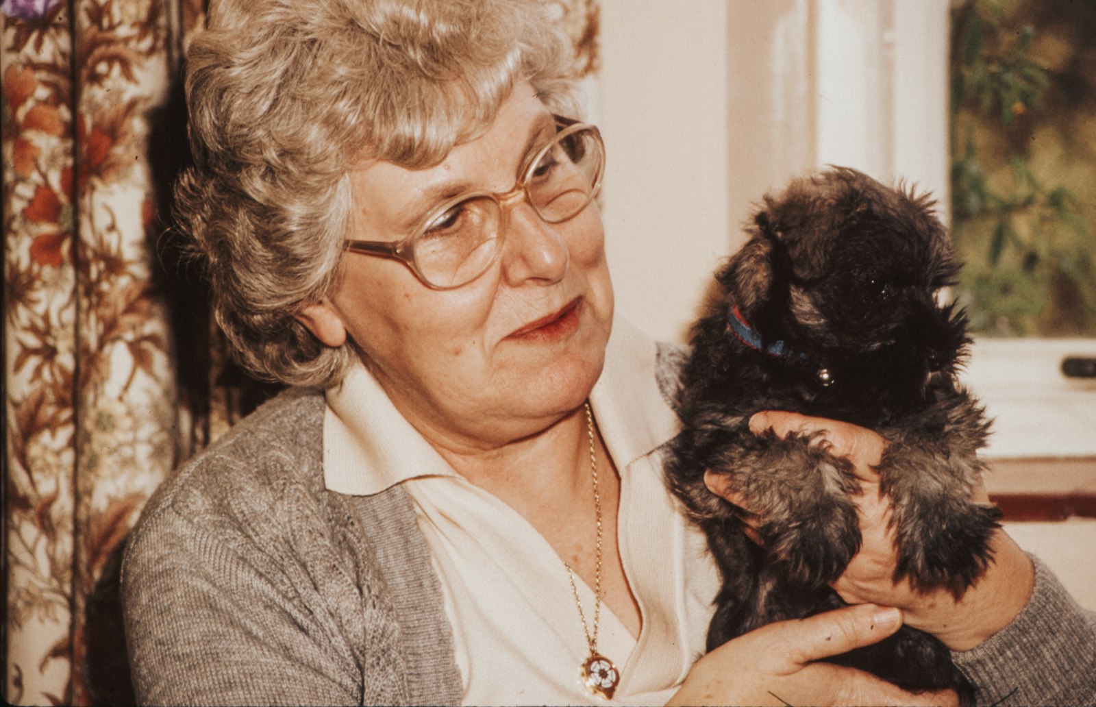 An older woman smiling while holding a puppy